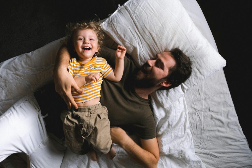 father waking up on the right side of the bed giggling with his child after visiting sleep apnea dentist in Manhattan