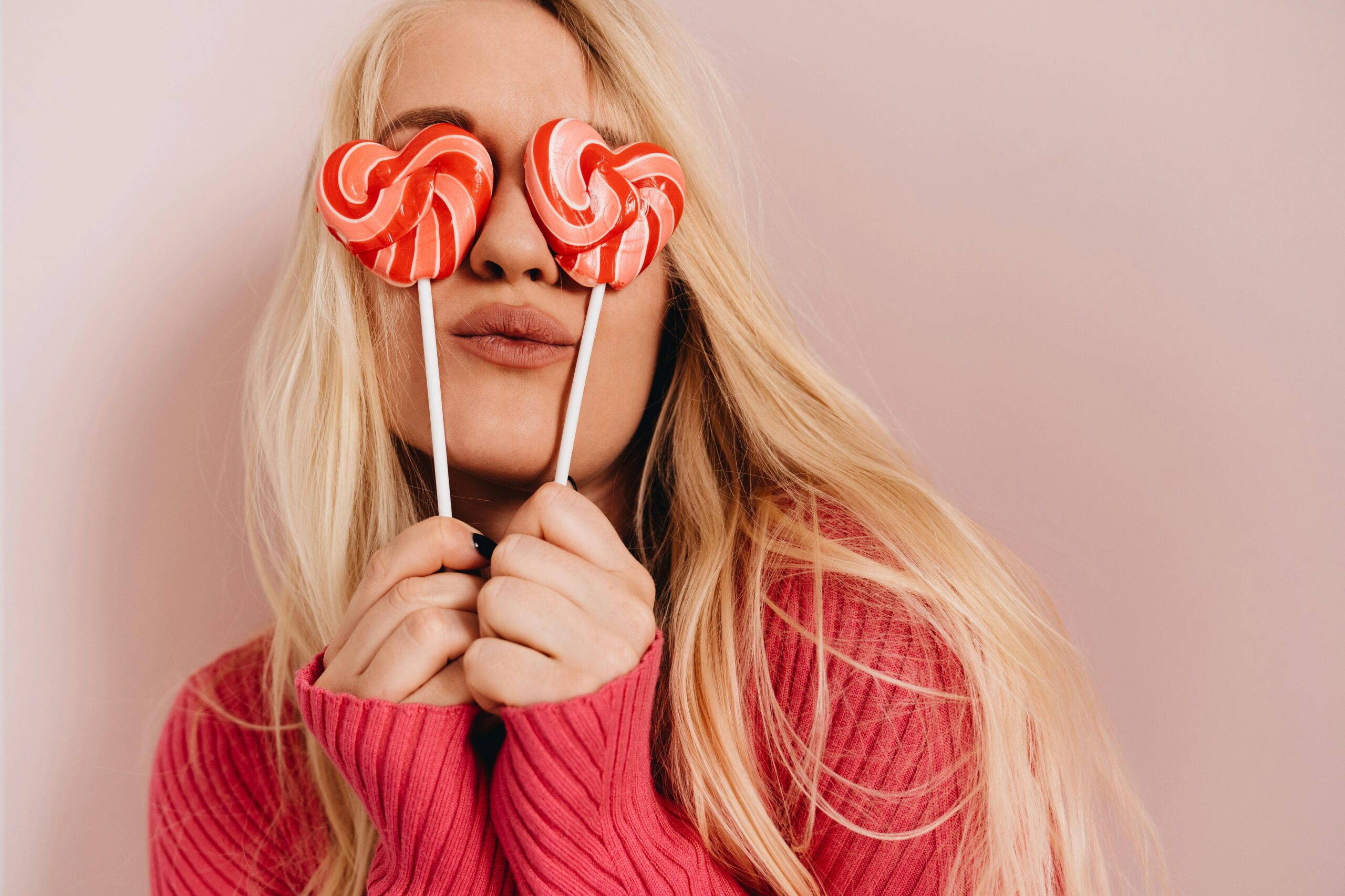 woman posing with heart-shaped lollipops before visiting our dentist near central harlem